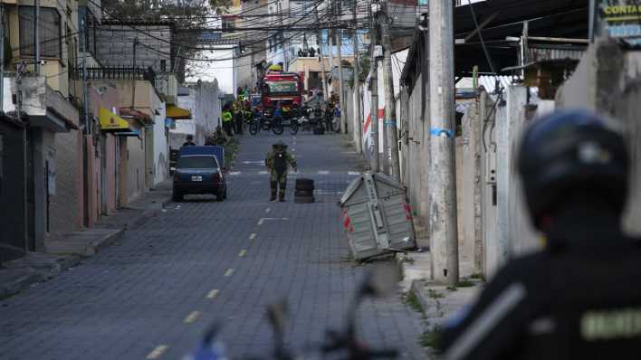 Die Polizei führt in Ecuador eine kontrollierte Explosion eines verdächtigen Fahrzeugs durch, das einen Häuserblock vom Gefängnis El Inca entfernt geparkt ist. (Bild: Carlos Noriega/AP/dpa)