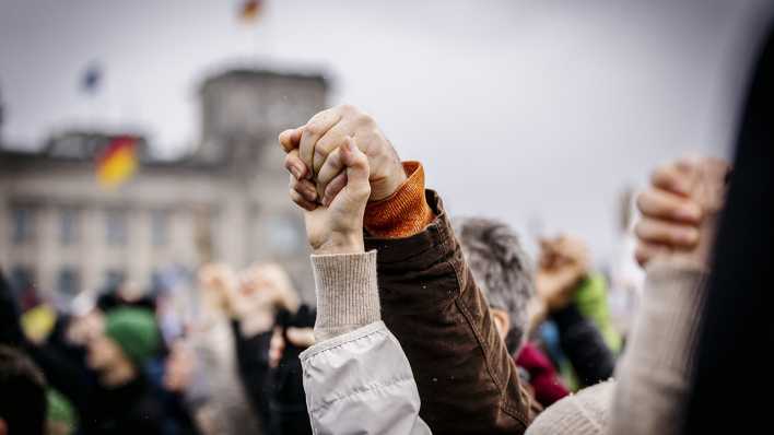 Menschen halten sich am Samstag auf der Großdemo gegen Rechtsextremismus vor dem Reichstag in Berlin an den Händen.