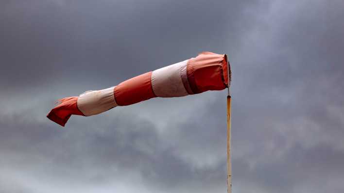 Ein rot-weißer Windsack weht im Sturm (Bild: picture alliance/Geisler-Fotopress/Christoph Hardt)
