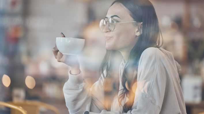 Eine Frau trinkt einen Kaffee in einem Café.