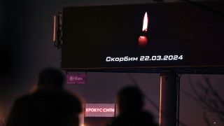 In Moskau laufen Menschen an einer Anzeigetafel vorbei, auf der eine Kerze für die Opfer des 22.03.2024 leuchtet.