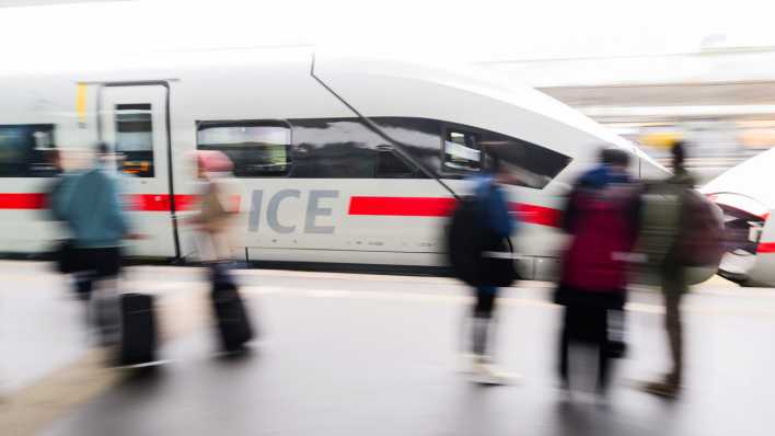 Reisende stehen auf dem Bahnsteig im Hauptbahnhof Hannover, während ein ICE einfährt (Bild: Julian Stratenschulte/dpa)