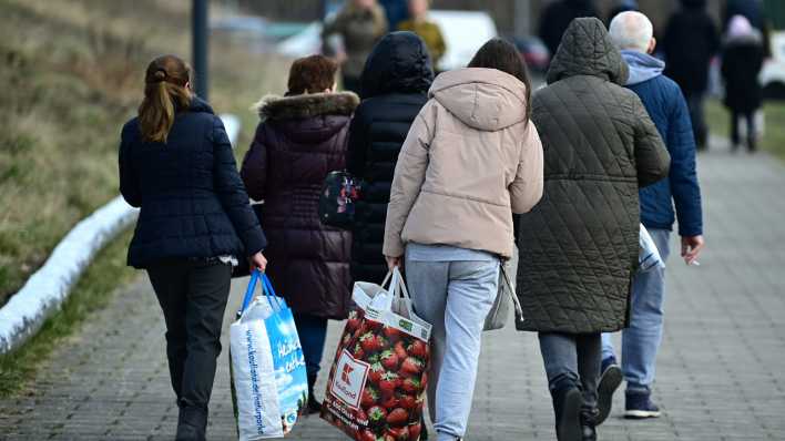 Ukrainische Flüchtlinge gehen nach ihrer Registrierung auf einem Weg entlang.