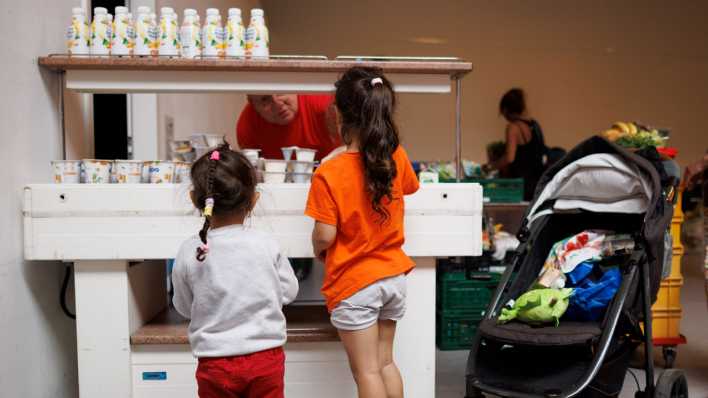 Ein Mitarbeiter verteilt Jogurt an zwei Kinder in der Ausgabestelle der Berliner Tafel. (Bild: dpa)