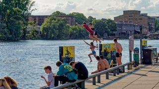 Teenager springen zum Baden in die Spree an der East Side Gallery in Berlin.