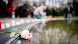 Eine Rose liegt bei einer Gedenkveranstaltung am Denkmal für die im Nationalsozialismus ermordeten Sinti und Roma Europas am Rande des Wasserbeckens.