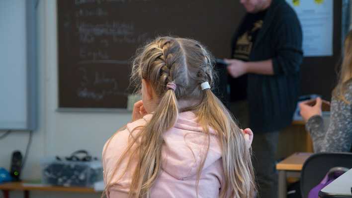 Ein Mädchen sitzt in seinem Klassenraum und verfolgt den Unterricht.