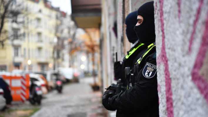 Polizeibeamte stehen bei einer Razzia in Berlin-Friedrichshain am Eingang eines Gebäudes.