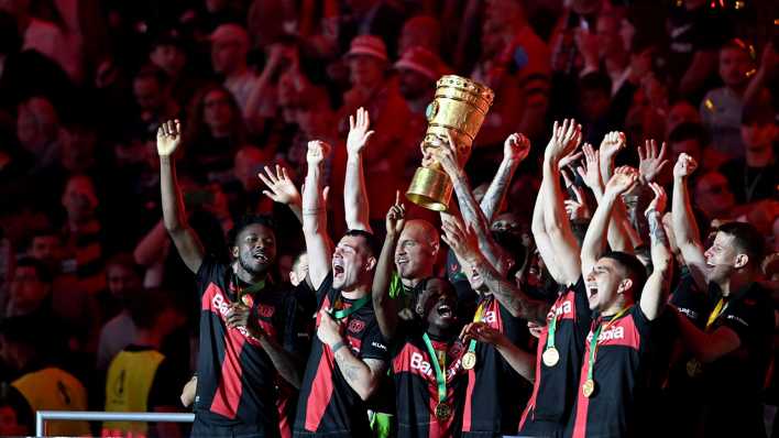 Leverkusens Mannschaft jubelt nach dem Sieg im DFB-Pokal gegen Kaiserslautern mit der Trophäe.