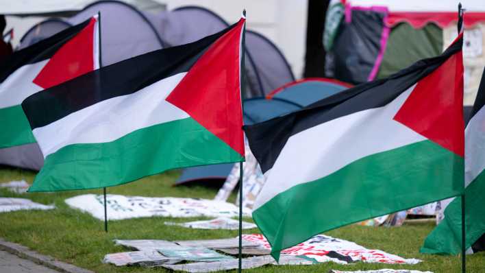 Palästinensische Flaggen stehen an einem propalästinensischen Protestcamp vor der Ludwig-Maximilians-Universität (LMU).