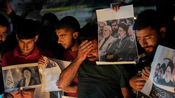 Ein schiitischer Muslim weint, während er Fotos des iranischen Präsidenten Ebrahim Raisi hält