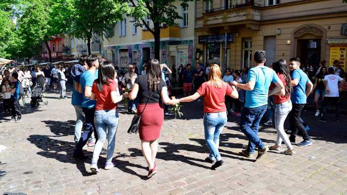 Menschen tanzen beim Berliner Hederlezi in Neukölln auf der Straße.