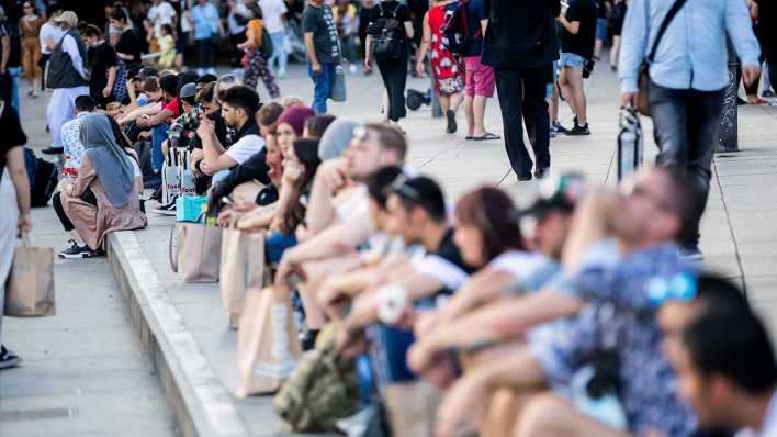 Passanten flanieren und sitzen am Berliner Alexanderplatz.