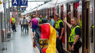 Sicherheitspersonal der Bahn weisst einem deutschen Fan den Weg zu einem freien Abteil (Bild: picture alliance/dpa | Andreas Arnold)