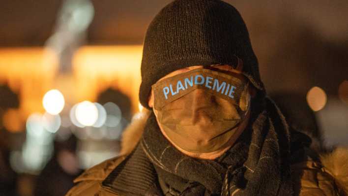 Ein Demo-Teilnehmer trägt einen Mundschutz mit dem Aufdruck "Plandemie".