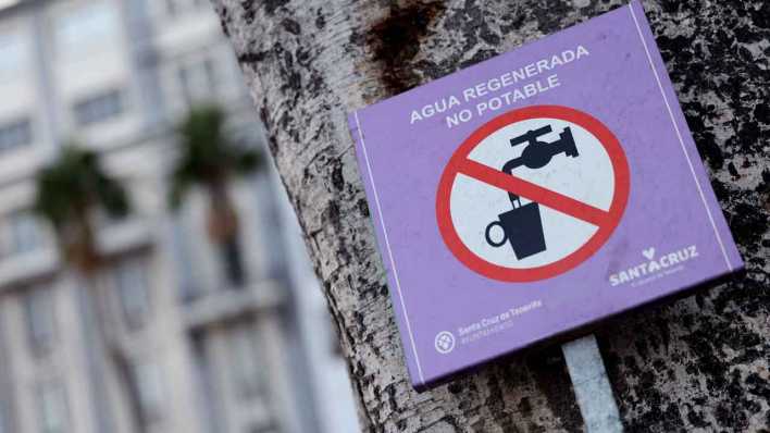 Ein Hinweisschild an einer Palme an der Promenade von Santa Cruz de Tenerife klärt Passanten darüber auf, dass es sich bei dem Wasseranschluss um wiederaufbereitetes und nicht trinkbares Wasser handelt.