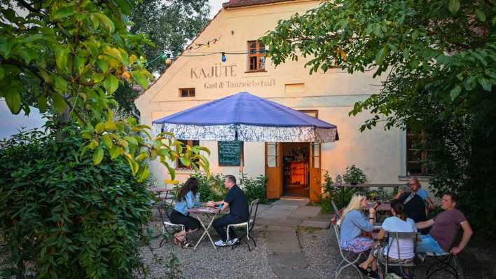 ARCHIV, 16.8.23: Im letzten Tageslicht sitzen Gäste im Garten der Gast- und Tanzwirtschaft Kajüte (Bild: picture alliance/dpa/Patrick Pleul)