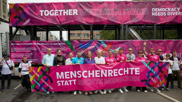 Teilnehmende des CSD in Berlin halten ein Banner mit der Aufschrift "Menschenrechte statt rechte Menschen".