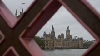 Blick durch ein Brückengeländer auf die Themse und das britische Parlament