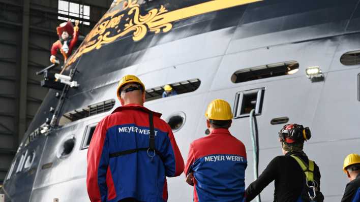 Mitarbeiter der Meyer Werft beobachten das Ausdocken eines Kreuzfahrtschiffs im Dock in Papenburg. (Bild: picture alliance/dpa/Lars Penning)