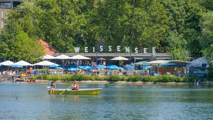 Ein Ruderboot fährt am Strandbad Weißensee vorbei.