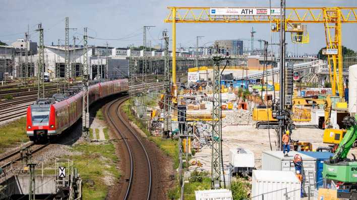 Ein Regionalzug fährt an einer Baustelle in München vorbei.