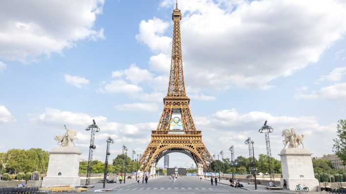 Am Eiffelturm in Paris hängt das Logo der Olympischen Spiele mit den Olympischen Ringen.