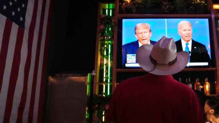 Ein Mann mit Cowboyhut in Arizona schaut sich in einer Bar das TV-Duell zwischen Joe Biden und donald Trump an. (Bild: picture alliance / ASSOCIATED PRESS | Ross D. Franklin)