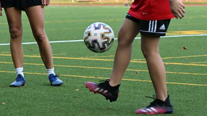 Symbolfoto: Ein Mädchen jongliert auf dem Fußballplatz mit einem Ball.