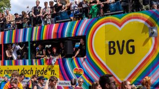 Ein mit Regenbogenfarben geschmückter Doppeldecker-Bus der BVG fährt im CSD-Demozug.