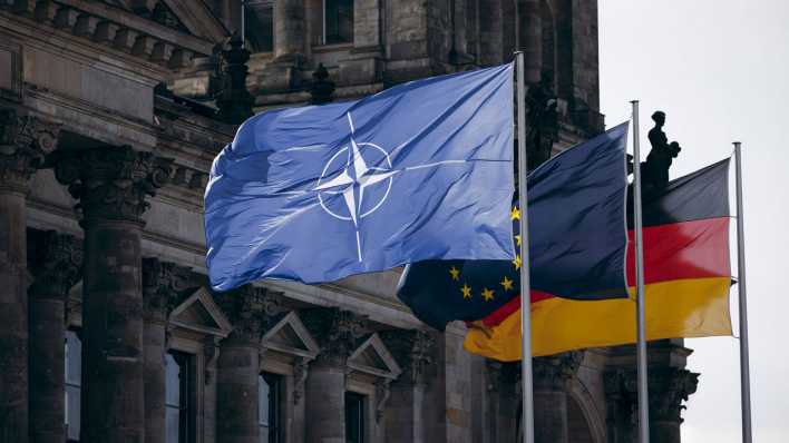 Die Flagge der NATO, Europas und der Bundesrepublik Deutschland aufgenommen am Reichstagsgebäude in Berlin (Bild: IMAGO/photothek/Felix Zahn)