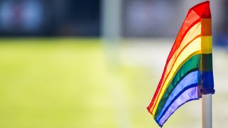 Eine Regenbogenflagge weht vor einem Fußballfeld