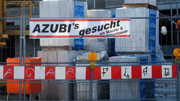 ARCHIV: Ein Schild "Azubis gesucht als Maurer und Betonbauer" hängt an einer Baustelle (Bild: picture alliance / Jens Kalaene)