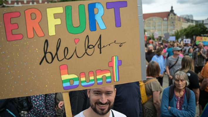 Ein Demonstrant hält ein Schild mit der Aufschrift "Erfurt bleibt bunt".