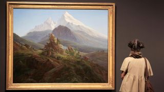 Eine junge Frau betrachtet das Gemälde "Der Watzmann" von Caspar David Friedrich.