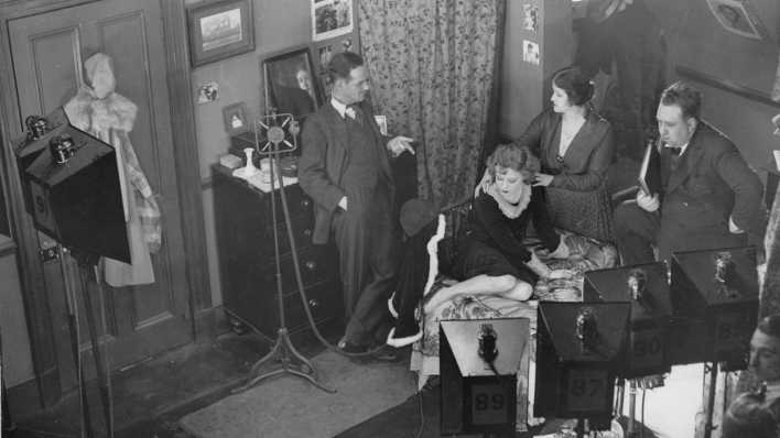 Alfred Hitchcock mit einem Buch in der Hand am Filmset von "Blackmail" (deutscher Titel: "Erpressung")