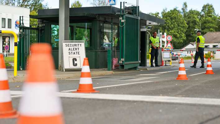 Sicherheitspersonal steht im Bereich der Einfahrt zur Nato Air Base, links der Hinweis auf den Security Alert State C.