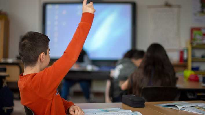 Ein Schüler meldet sich während des Unterrichts in einer Grundschule mit Handzeichen.