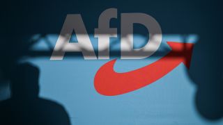 Ein Redner wirft einen Schatten auf die Bühnenrückwand mit AfD-Schriftzug auf einer Veranstaltung.