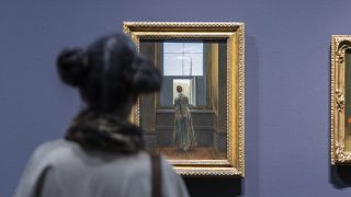 Eine Ausstellungsbesucherin steht vor dem Gemälde "Frau am Fenster" von Caspar David Friedrich.