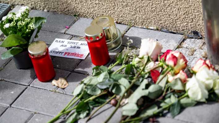 Blumen und Kerzen liegen nach einem tödlichen Messerangriff vor einem Hauseingang in Berlin-Friedrichsfelde neben einem Zettel mit der Aufschrift "Man tötet nicht aus Liebe - Stoppt Femizide".