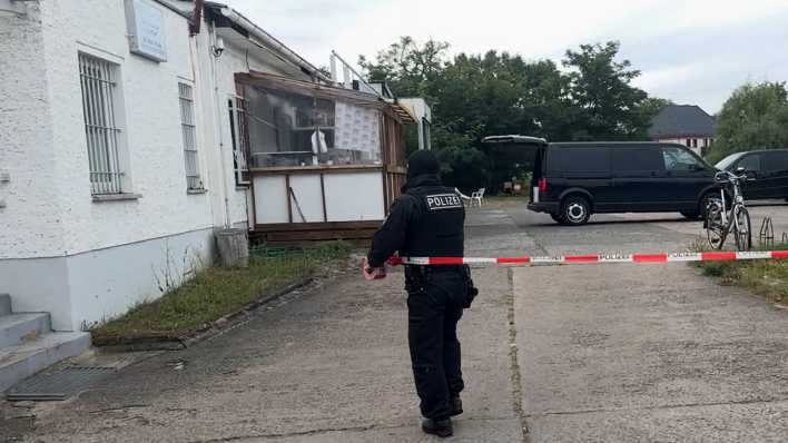 Ein Polizist bringt bei der Durchsuchung von Räumen des Islamischen Zentrums in Fürstenwalde Flatterband für eine Absperrung an.