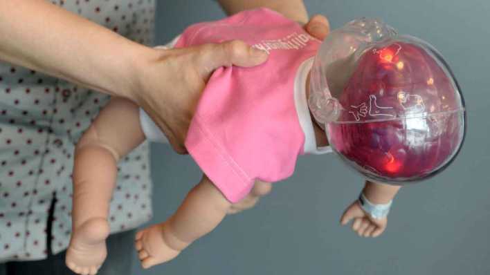 Leuchtende rote Lämpchen im Kopf der Simulationspuppe "Shaken Baby" markieren nach dem Schütteln der Puppe die Hirnregionen, die durch das Schütteln beim echten Baby geschädigt werden (Bild: picture alliance/Franziska Kraufmann/dpa)