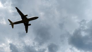 Gewitterwolken türmen sich über einem landenden Flugzeug auf.