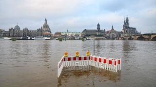 Absperrungen stehen gegenüber der Altstadtkulisse Dresden auf den von der Elbe überfluteten Elbwiesen.