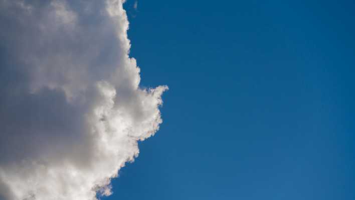 Eine weiße Wolke steht am blauen Himmel.