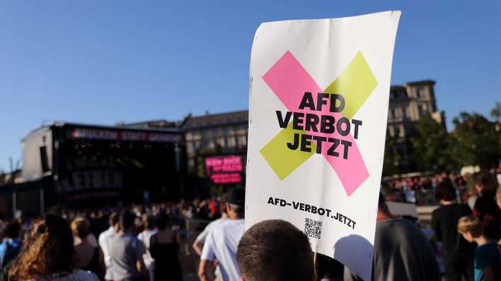 Ein Demonstrant mit Schild "AfD Verbot Jetzt" während einer Kundgebung in Potsdam.