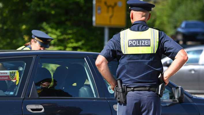 Polizisten kontrollieren Fahrzeuge und Fahrzeugpapiere.