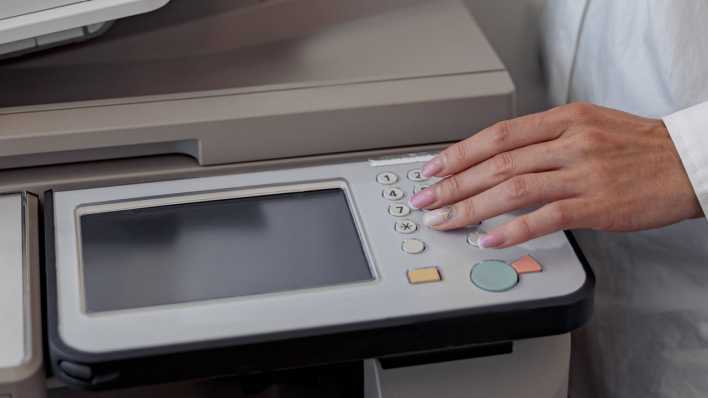 Frau steht an einem Drucker/Scanner