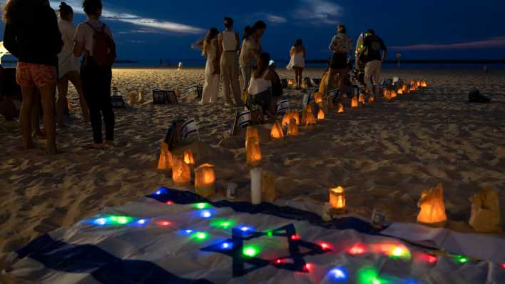 Freunde der Hamas-Opfer des Nova-Festivals in Südisrael entzünden Kerzen an einem Strand in Tel Aviv im November 2023 (Bild: picture alliance/AP/Oded Balilty)